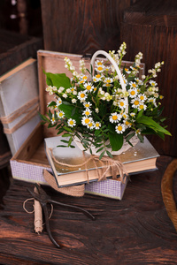 洋甘菊装饰组成与书和褐色的木桌上的盒子
