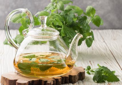 在木材上梅香在表和新鲜梅丽莎 (柠檬香蜂草) 和薄荷枝上的透明茶壶的
