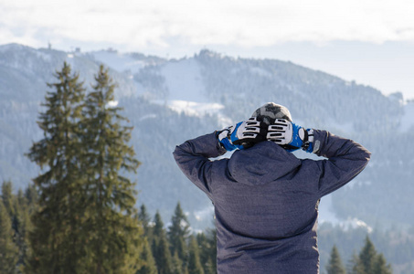 少年人放松在冬季夹克在山的后面观