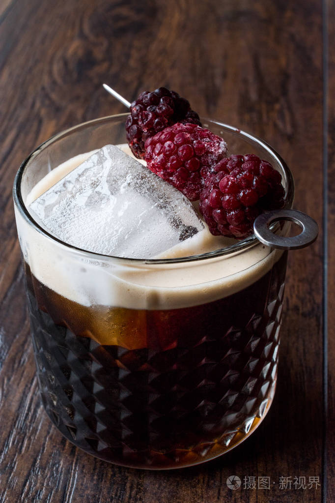 黑黑啤酒鸡尾酒与黑莓和冰在木表面