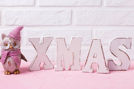 词圣诞节由木信件和装饰的玩具猫头鹰在粉红色背景反对白色墙壁。文本位置