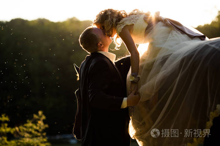 新郎亲吻新娘,握住她的手,而她坐在餐前照片-正版商用图片0njq81-摄图