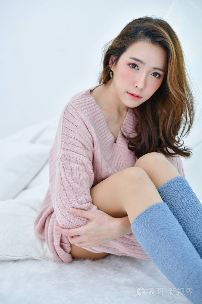 冬天的概念可爱的亚洲女孩穿着冬衣美丽的女人在白色的卧室里放松穿着