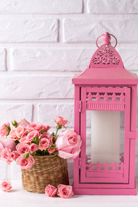 粉红色玫瑰花和装饰粉红色灯笼反对白色砖墙。花静物。选择性对焦。文本的位置。垂直图像