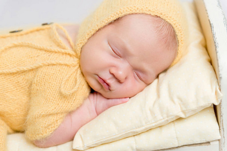 婴儿穿着针织黄色服装睡在婴儿床上