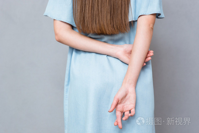 关闭交叉手指在女人的背后