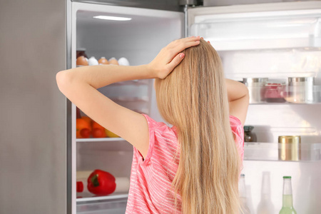 厨房附近打开冰箱的年轻妇女