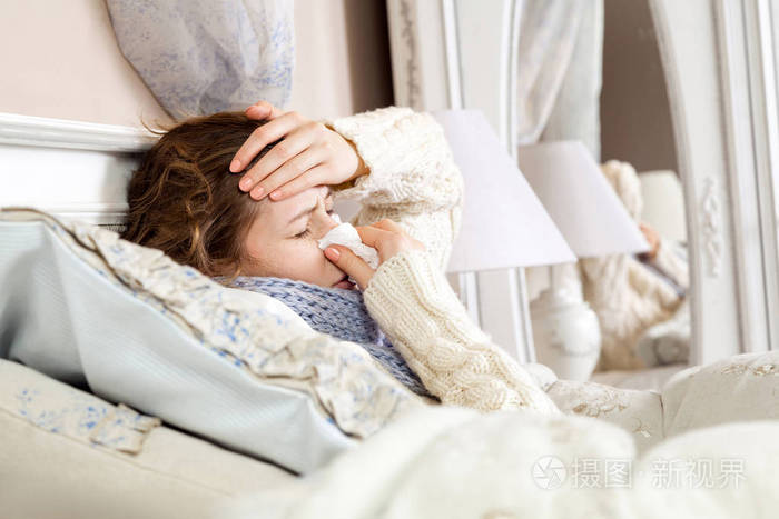 特写镜头的郁闷生病的女人躺在床上厚厚的蓝色围巾举行组织她的鼻子