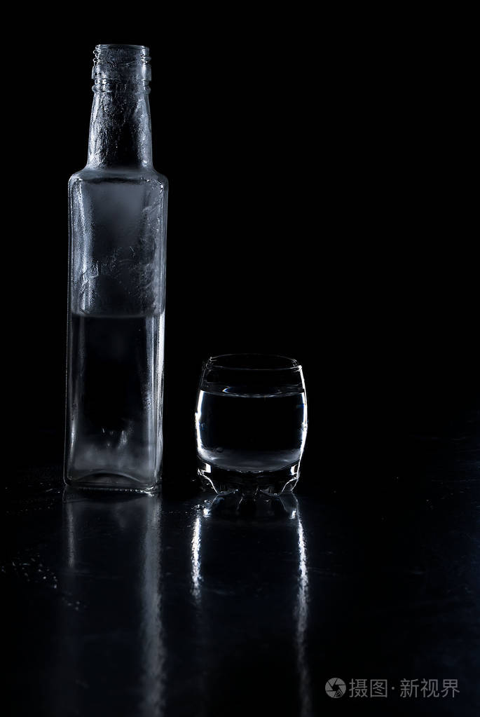 瓶冰冻伏特加和黑色背景上的玻璃