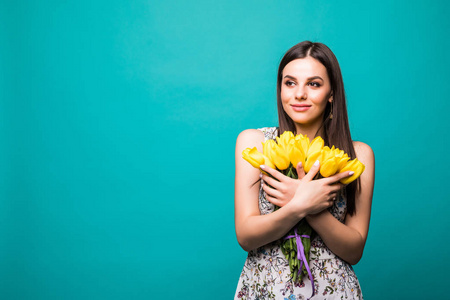 一个美丽的年轻女子的肖像 ssummer 礼服持有黄色郁金香花束孤立的蓝色背景