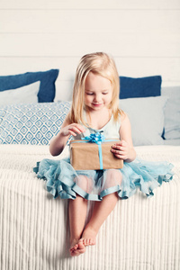 可爱的孩子女孩开放礼物与蓝丝带