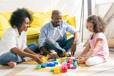微笑的非洲裔美国人家庭玩五颜六色的积木一起在地板上在家