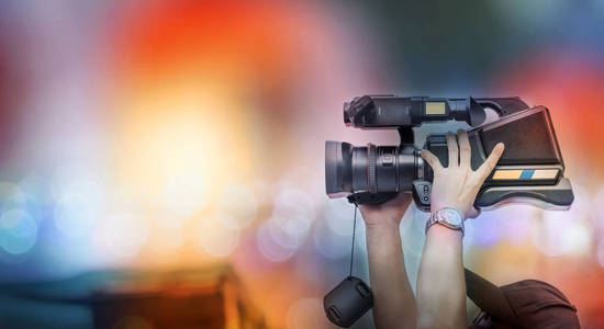 摄影师在拍摄视频时将摄像机抬到头顶上方.照片