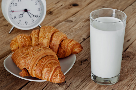 早上早餐牛奶和牛角面包放在木桌上