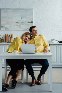 夫妇喝咖啡和用膝上型电脑拥抱