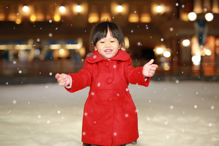 快乐笑蹒跚学步的女孩穿着一件红色的夹克有着一段有趣的雪，冬天的时候