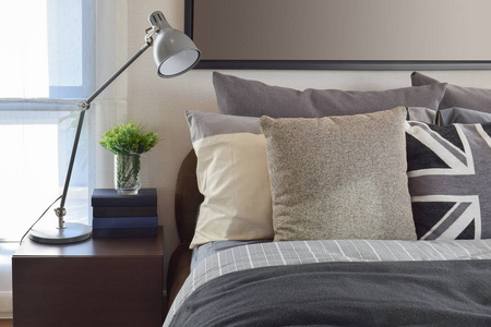 现代卧室灰色枕头和木制床头柜上的灯