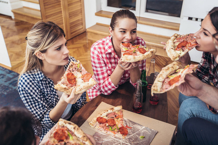 一群年轻的朋友吃比萨饼。家庭聚会快餐概念