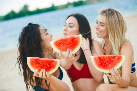 年轻有魅力的愉快的妇女与西瓜在海滩乐趣