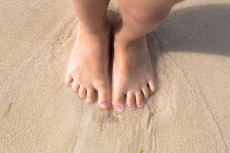 在海滩的视图赤脚小子少站在海滩上的沙子,顶视图照片