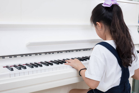 亚洲中国小女孩在玩古典钢琴在家里