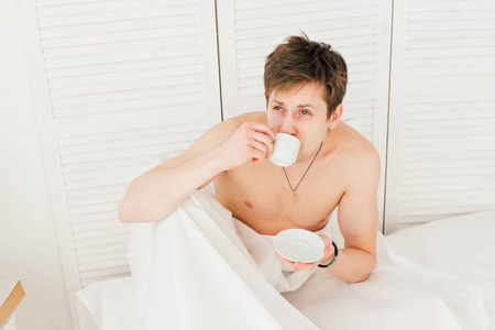 在早餐喝咖啡，躺在床上的男人