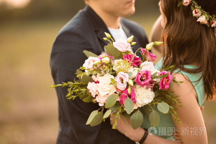一对年轻夫妇在爱户外日落-男人送花