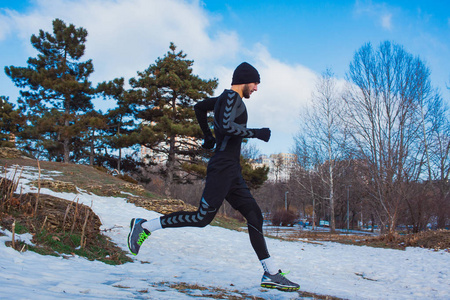 年轻的跑步者在冬季公园山上培训照片