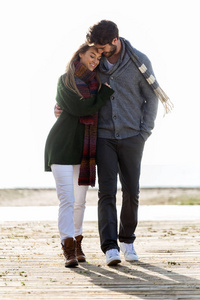 美丽的年轻夫妇，在海滩上散步，在一个寒冷的冬天的爱