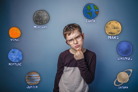 戴眼镜的十几岁男孩认为太阳系的行星