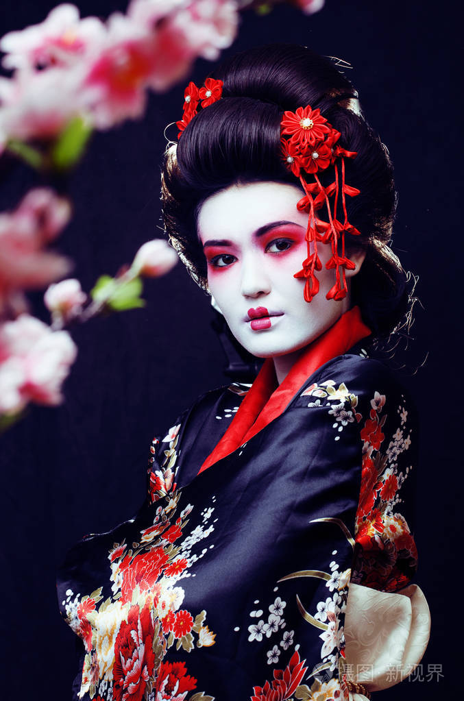 年轻漂亮的真正艺伎和服与樱花和装饰