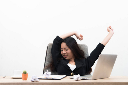 年轻的商业女性看起来压力和疲惫坐在工作场所与笔记本电脑上的桌子上孤立的白色背景