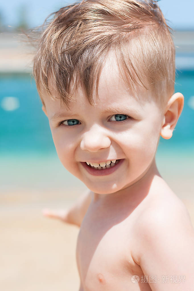 漂亮的小男孩微笑着在沙滩上