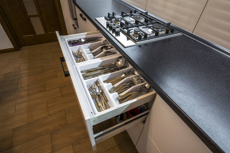 不锈钢勺子, 刀叉和刀在白色厨房橱柜的餐具箱抽屉里