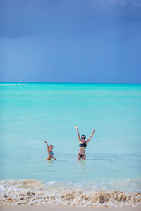 美丽的母亲和女儿在加勒比海滩。海滩度假家庭