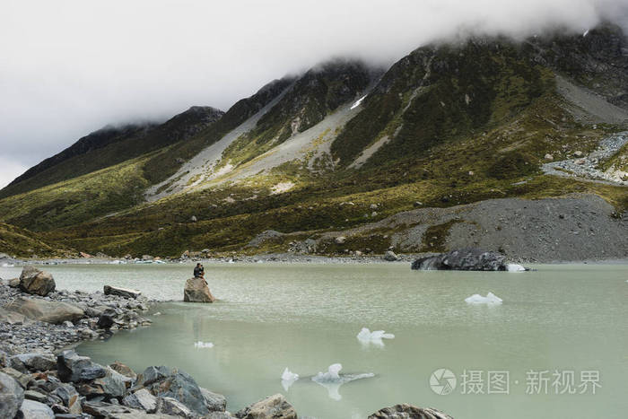 高山与多云山峰之间的绿河景观