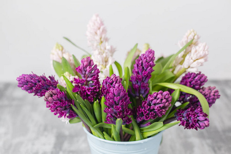 美丽的紫罗兰和粉红色的风信子花束。春天的花朵在花瓶上灰色的桌子背景。球茎植物