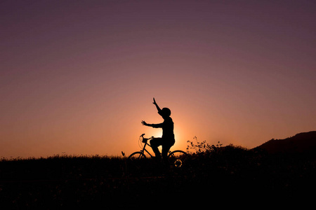 快乐的人在自然的日落上自行车的剪影