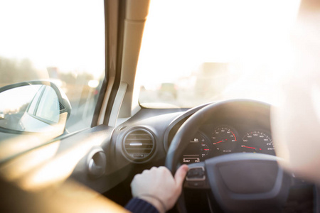 人在日落时开车。内部视图。方向盘上的手