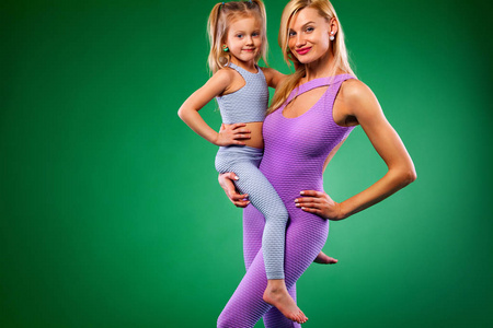 哈他瑜伽健身。年轻的母亲和女儿一起在室内锻炼。家庭外观