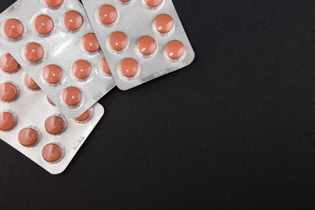 黑色背景下的包装上的药片照片