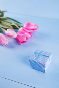 束粉红色郁金香与礼品盒上蓝色的木制背景