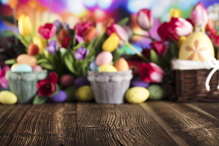 复活节背景。质朴的木桌。郁金香和春天的花朵。复活节彩蛋。多彩的散景。排版地点