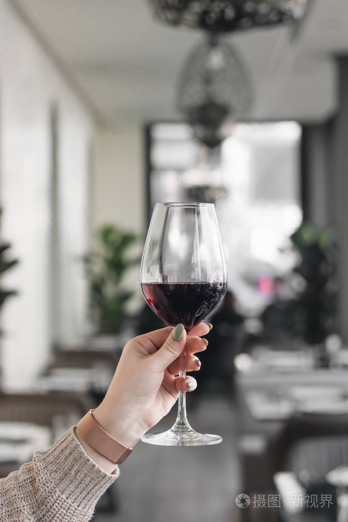 女性手捧酒杯在咖啡厅桌上的红酒照片-正版商用图片0nn7v3-摄图新视界