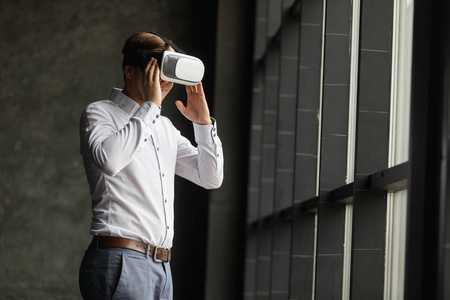 年轻人穿上虚拟现实眼镜现代室内设计中。智能手机使用与虚拟现实的护目镜耳机。横向的 模糊的背景