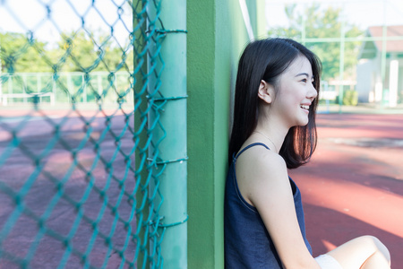 美丽的亚洲女孩后打网球网球场上