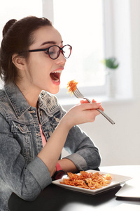 在室内吃美味面食的年轻女子