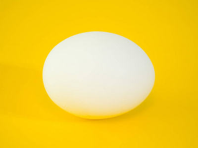特写照片一个真正的大白鸡鸡蛋在充满活力的黄色实心彩色切割板背景下, 为复活节假期的美丽的眼睛捕捉背景