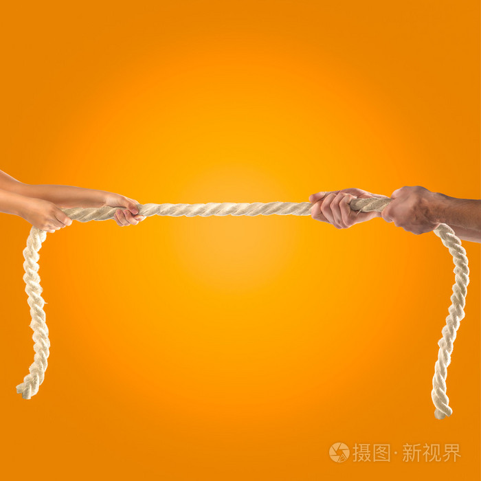 手女孩和成年男子用力拉绳子上橙色背景竞争理念