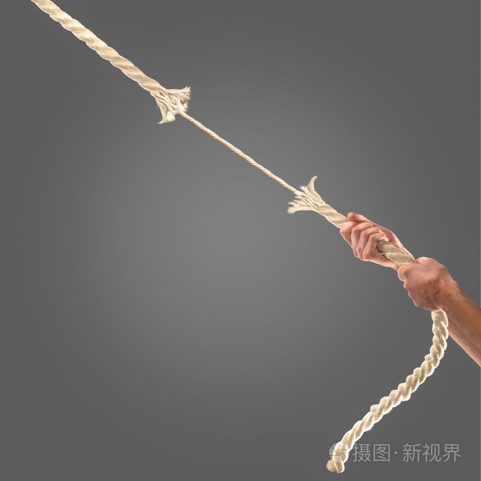 在黑色背景上用力拉绳子的人的手里.竞争理念